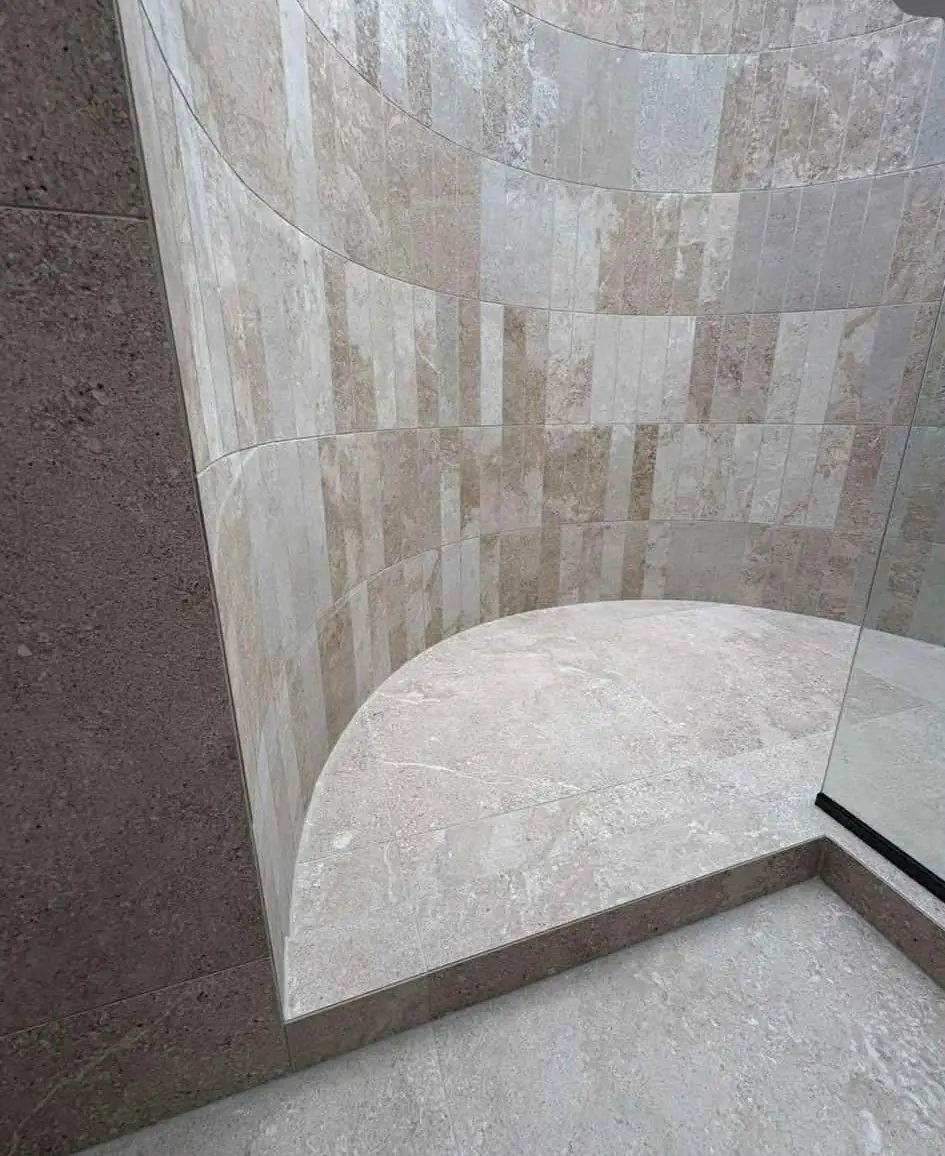 Curved tiled shower wall with a stone-look finish