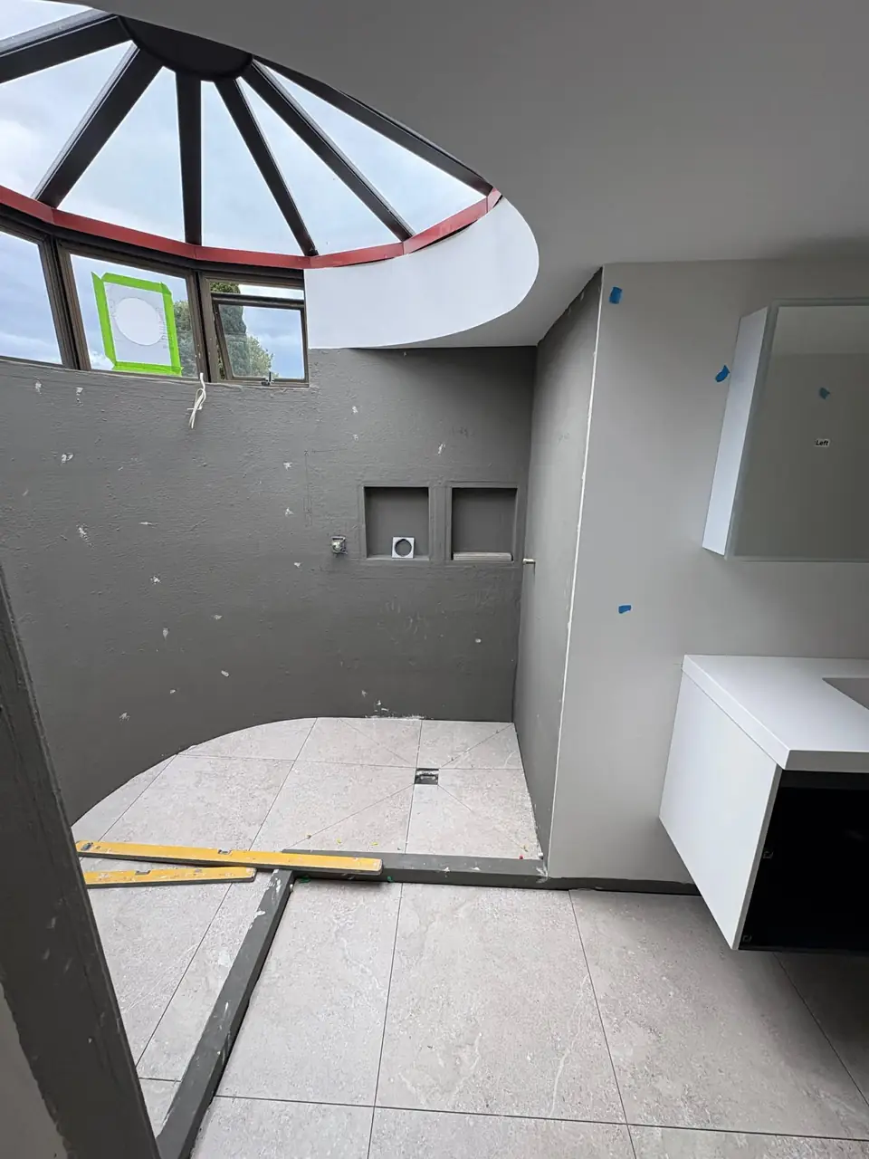 Bathroom mid renovation under a round skylight, walls lined and waterproofed