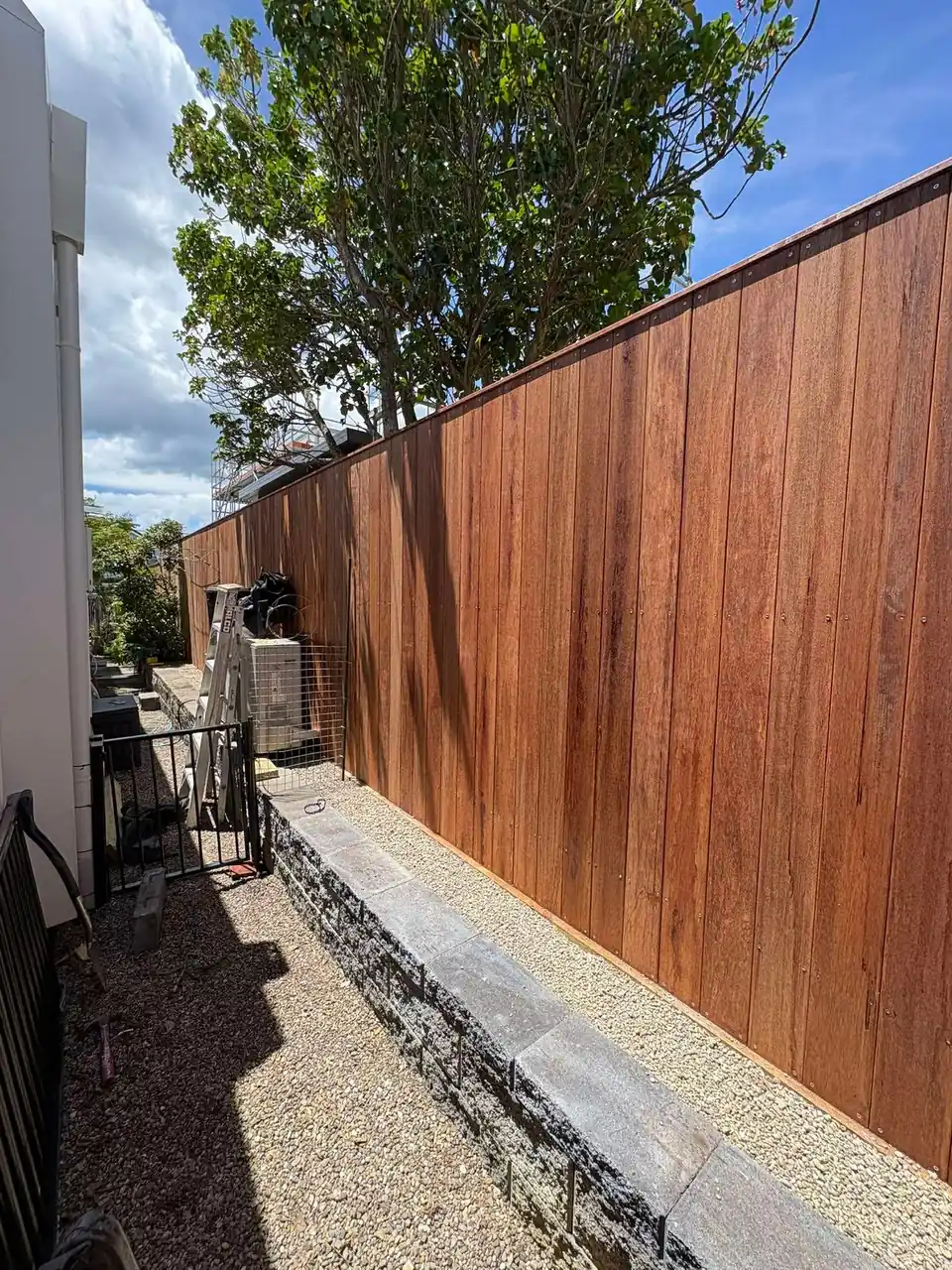 Hardwood boundary fence with a gravel path