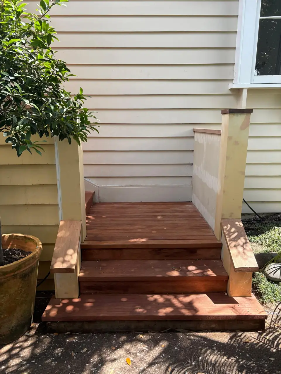 Front view of new hardwood porch steps against a weatherboard wall