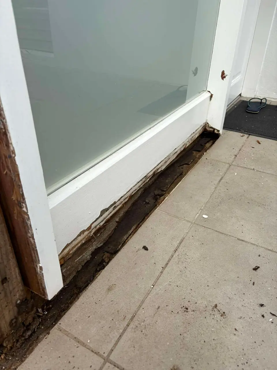 Rot damage at the corner of a door frame before repair