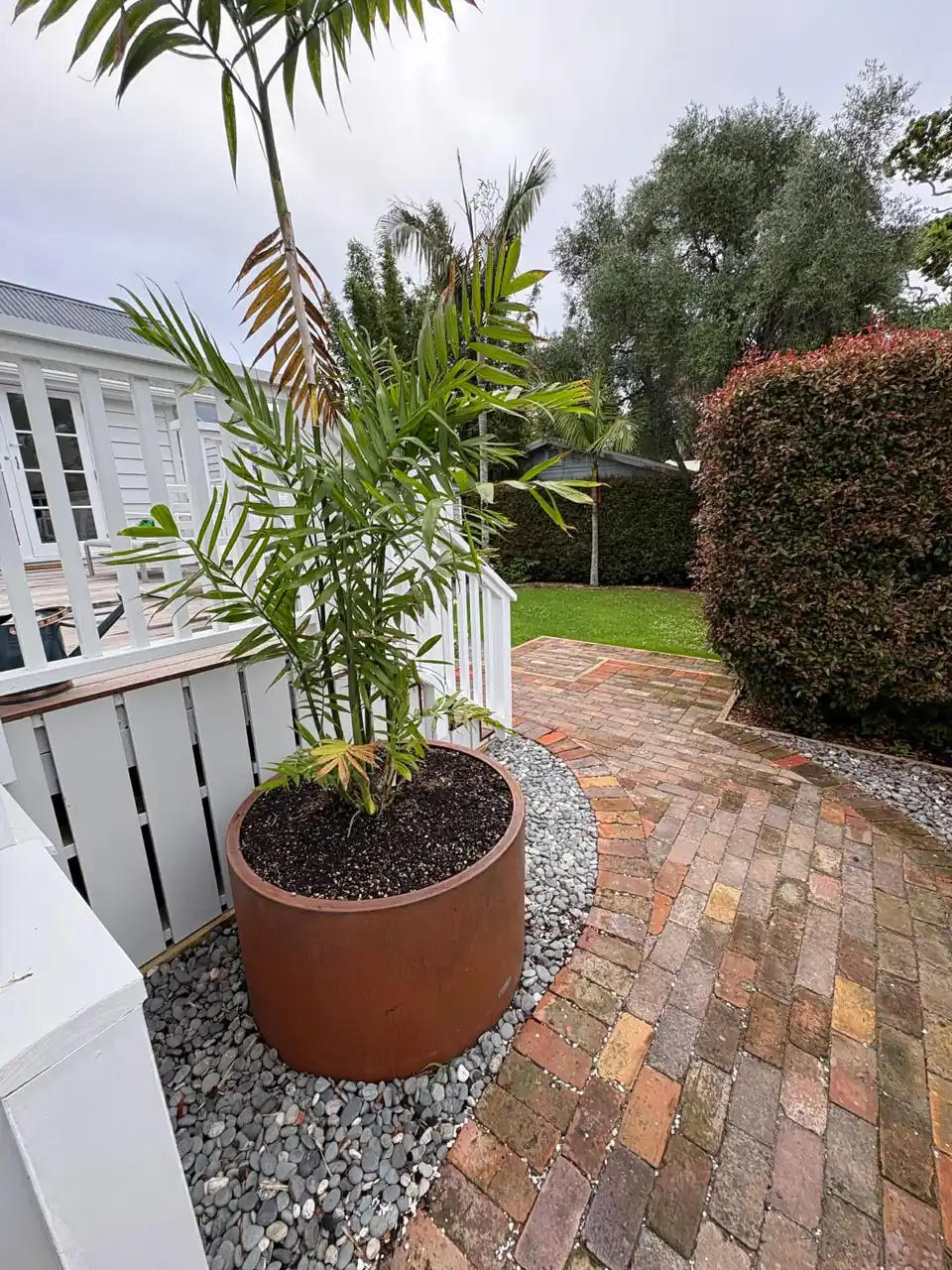Herringbone brick path with a corten planter and white balustrade