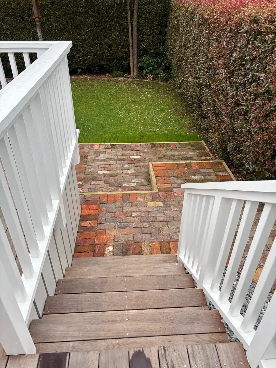 White painted villa steps leading down to a brick path and lawn